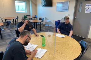 X shaped acrylic face shield dividing a break room table